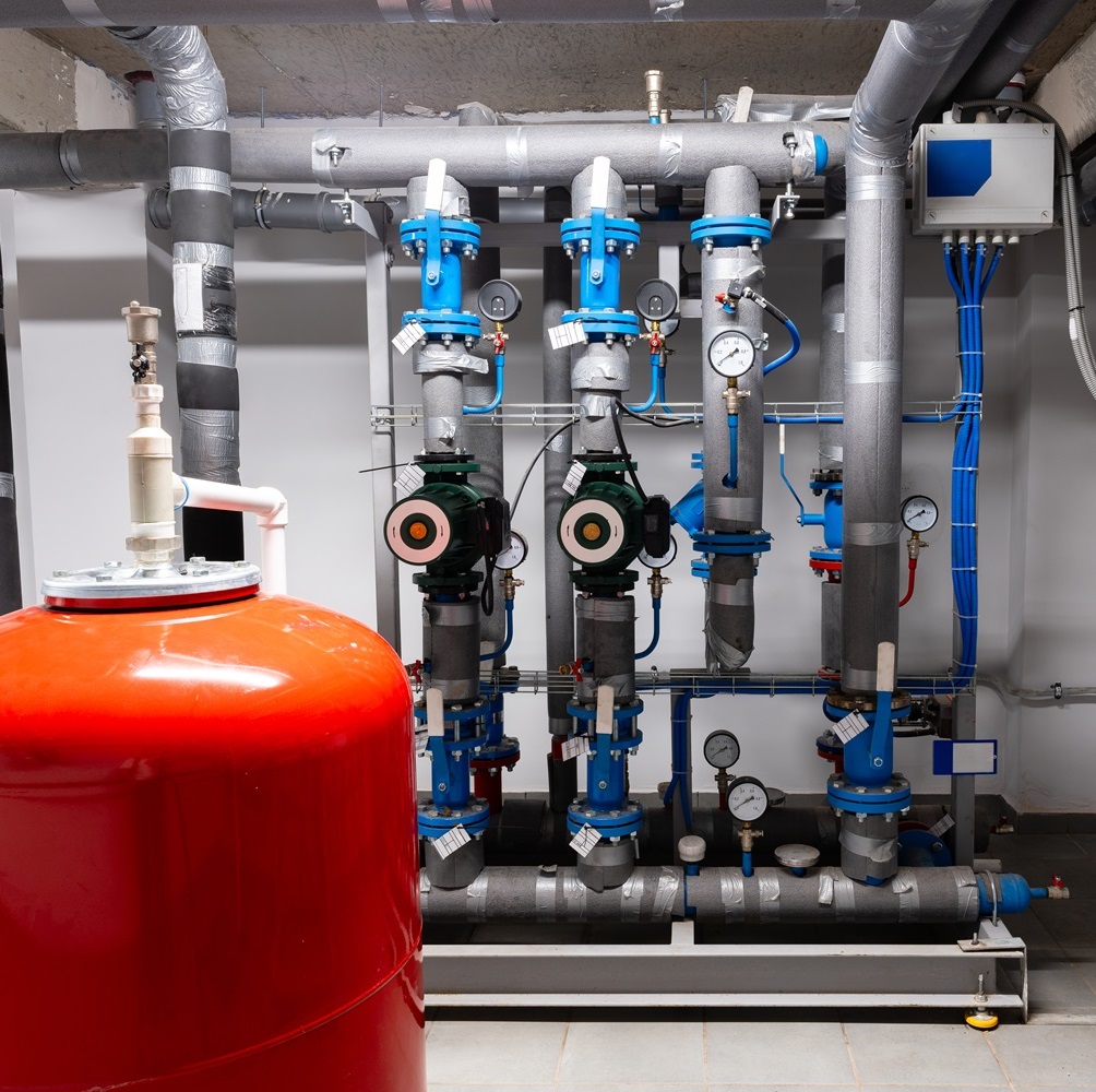 Modern plumbing system with red tank and blue valves in a mechanical room